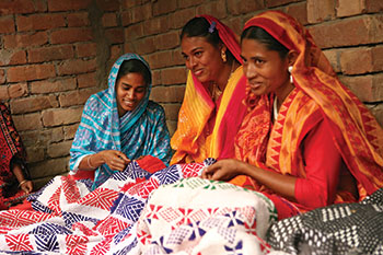 Mossamad Sabina Begam (in blue at left), works with women from her village on a Nakshi Kantha project. The Song of a New Life in Bangladesh