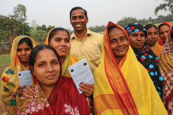 Mohammad Huzzatullah joins women from the group he started as they proudly display their savings records. The Song of a New Life in Bangladesh