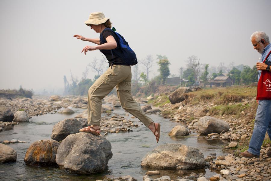 Heifer Board member Sandra Godden leaps river rocks on her way to the Heifer project village Shaktikhor. Photo by Geoff Oliver Bugbee.